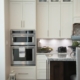 white wooden kitchen cabinet and stainless steel microwave oven